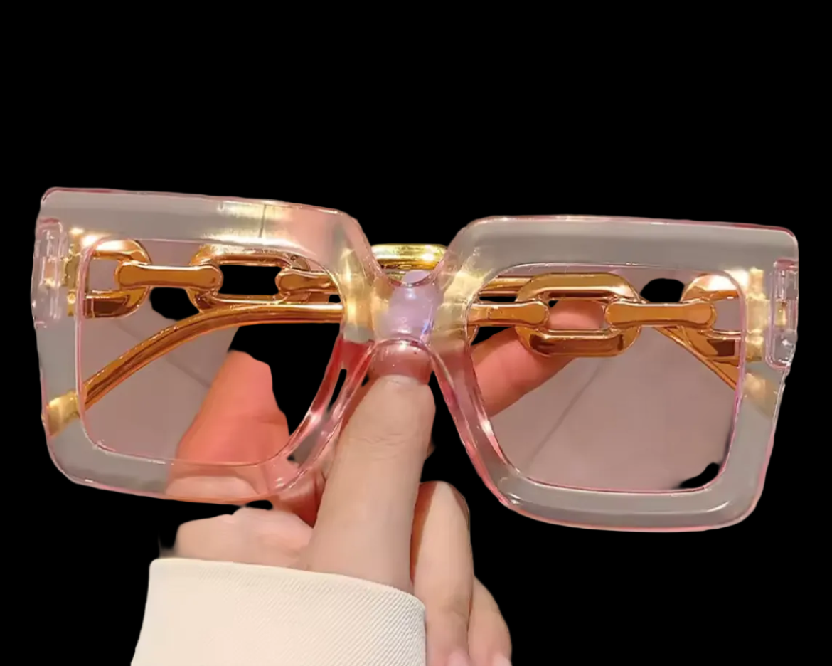 Sunglasses with gold accents held by a hand against a black background