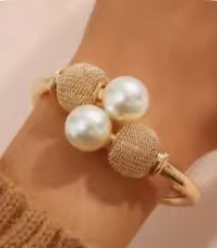 Gold bracelet with pearl-like beads on a wrist